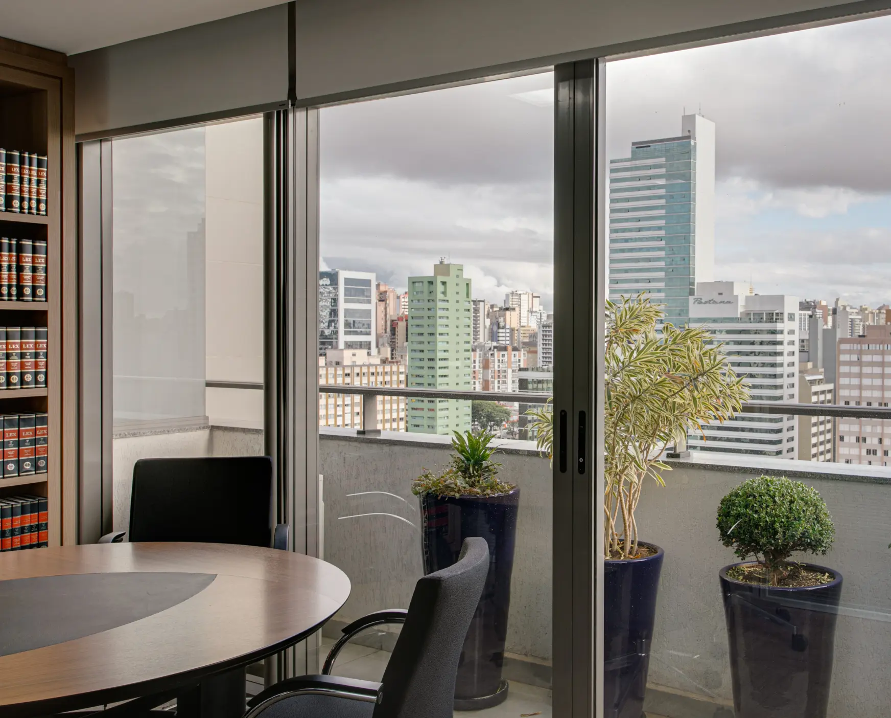 Escritório de advocacia de direito previdenciário e direito do trabalho localizado em Curitiba. Sala de atendimento com mesa de madeira e estante ao fundo.