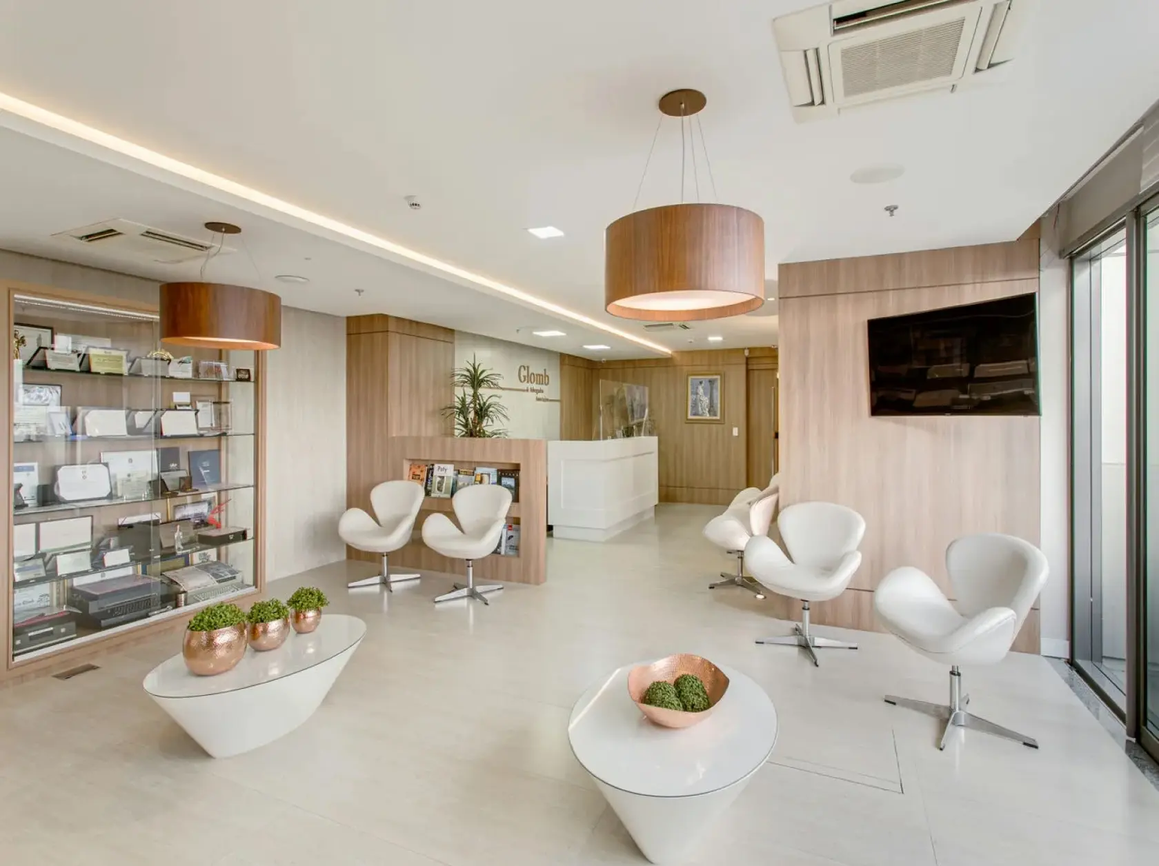 Recepção do escritório Glomb Advogados, advocacia especializada em direito do trabalho e previdência social. Entrada com piso de mármore, balcão branco e cadeiras de couro modernas.